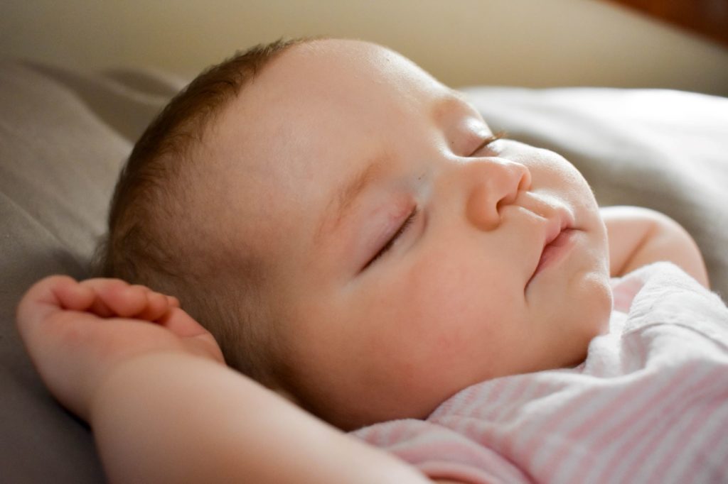 Why is my newborn baby sleeping with their arms up?